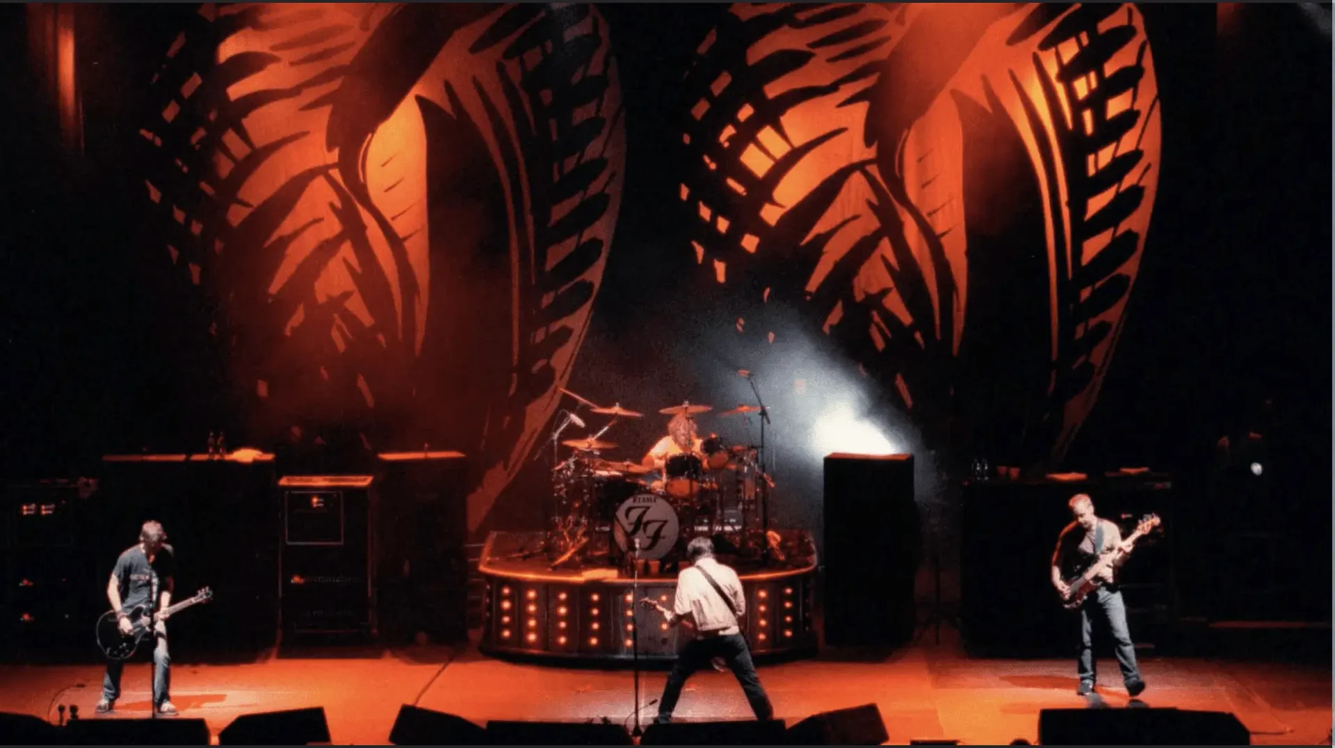 Three-piece rock band on orange-lit stage