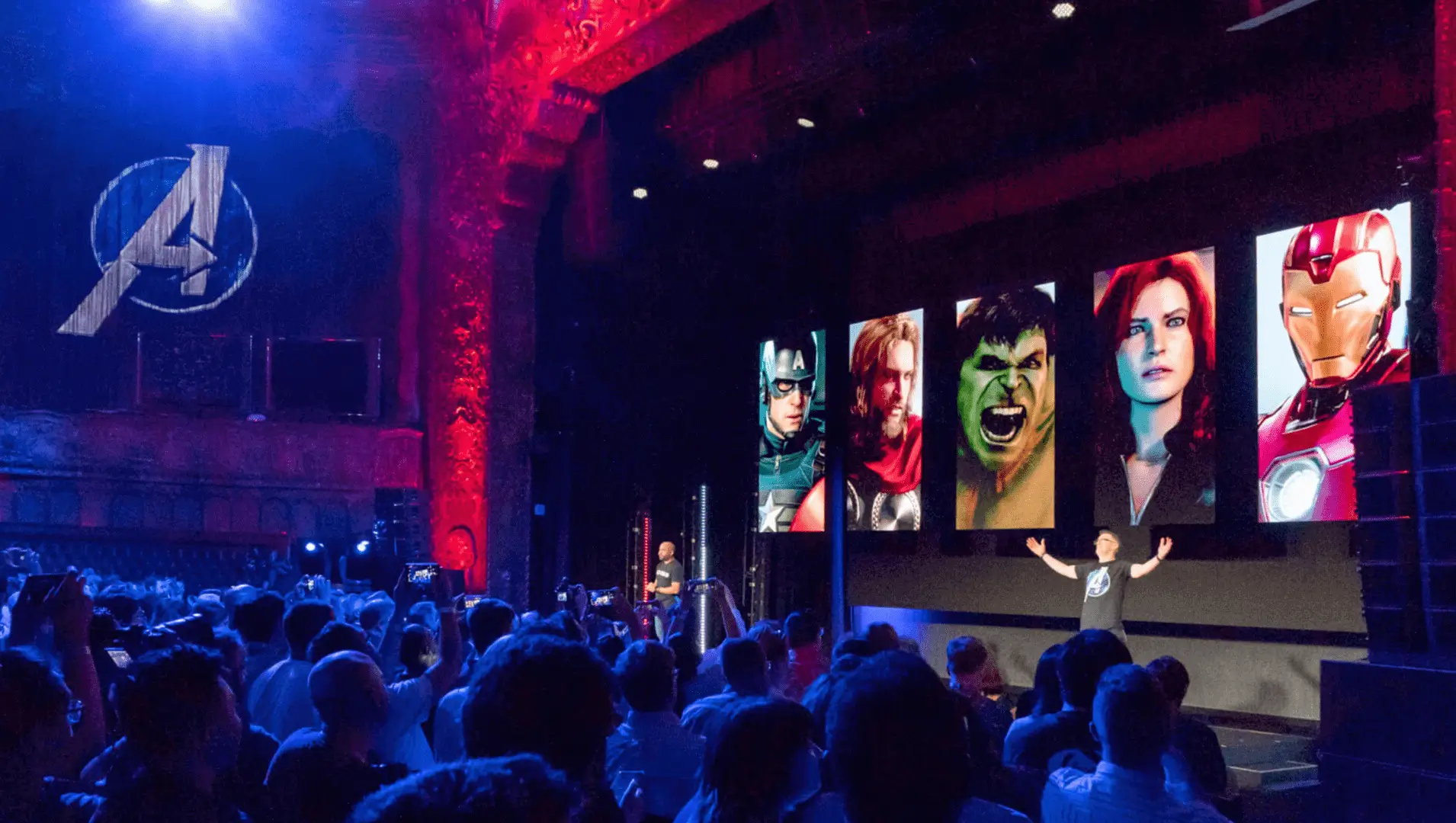 Presenter on stage with superhero portraits.