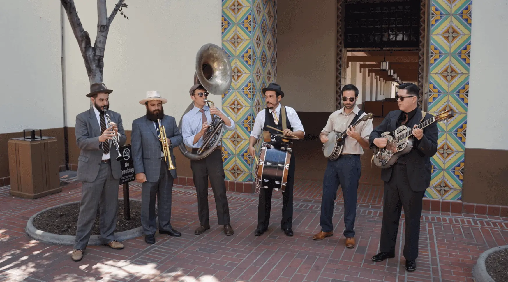 Six-piece band outdoors near tiled wall