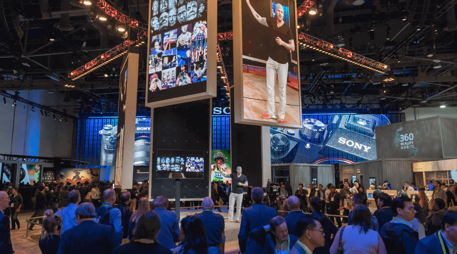 Hanging video walls tower over attendees.